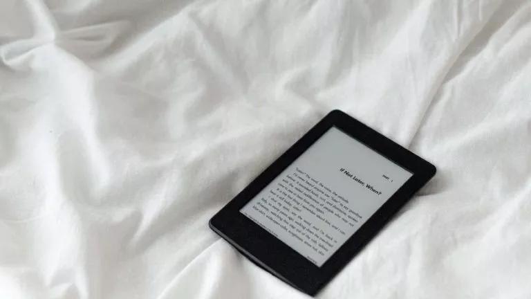 A Kindle on a white bedsheet