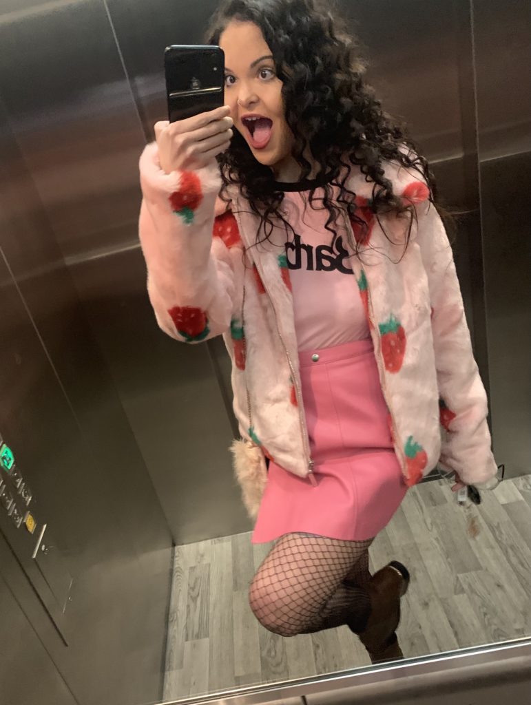 I’ve got long black curly hair and a pink coat with strawberries on